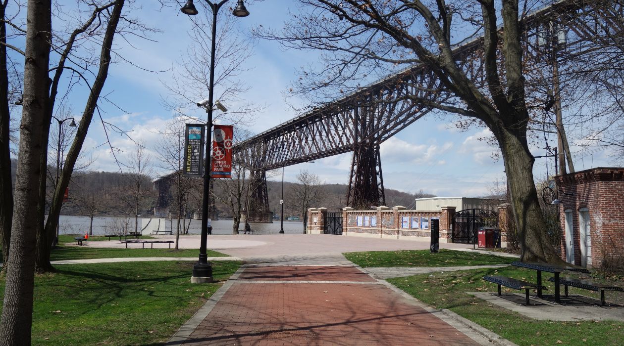 Upper Landing Park in Poughkeepsie, with its brick walkway and ornate lampposts with the Hudson River and the Walkway Over the Hudson in the background.